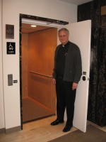 Father Robert Schulte stands at the door to the new elevator at MacDougal Chapel.