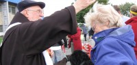 Mary Mac Donald receives the blessing from Franciscan Father Jim Kendzierski while holding her 10-year-old Dachshund named Solow.